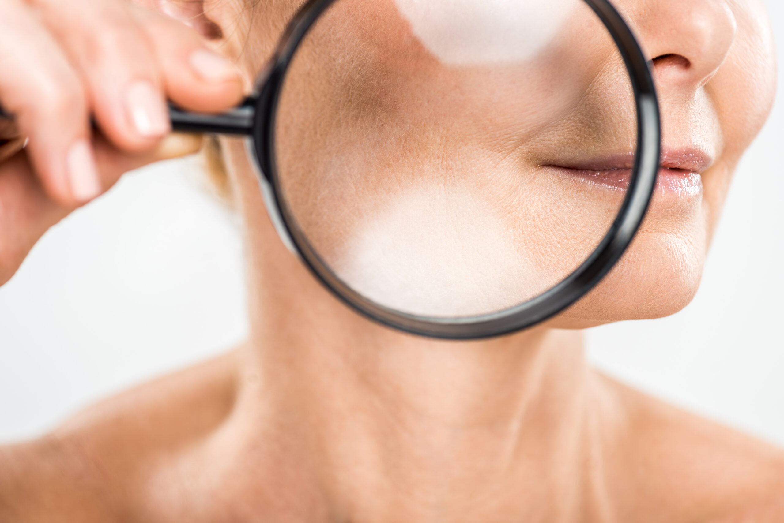 selective focus of mature woman holding loupe isolated on grey Frau zieht im Stehen Kompressionshose an