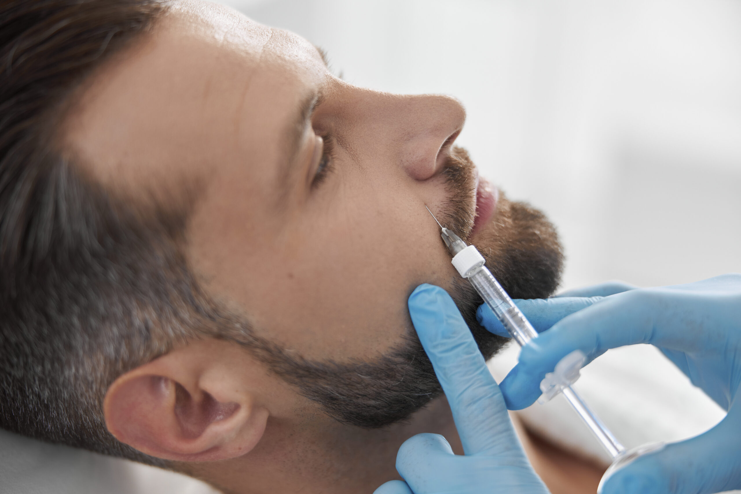 Mature person with beard undergoes nasolabial fold filler procedure with skilled beautician in salon Mature person with beard undergoes nasolabial fold filler procedure with skilled beautician in salon